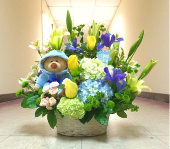 Basket arrangement with a teddy bear, lilies, tulips, and hydrangeas