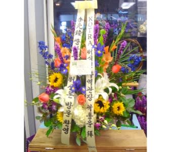 Tall mixed flower arrangement with sunflowers, lilies, roses, and irises with vertical message ribbons