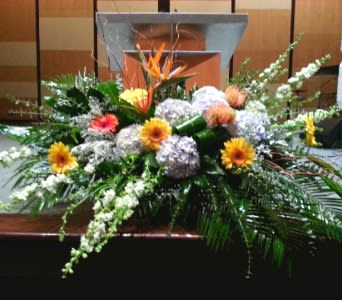 Large low centerpiece of hydrangeas, gerbera daisies, and a tropical bloom in front of a podium