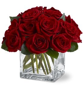 Red roses arranged in a clear square glass vase