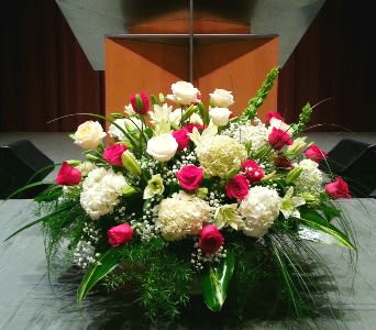 Large altar-style arrangement of red and white flowers with lilies and hydrangeas.