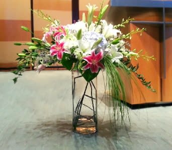 Tall floral arrangement with pink and white lilies in a metal stand