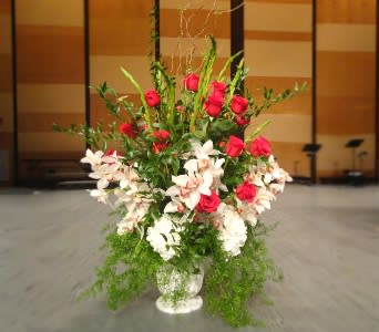 Tall arrangement of red roses and white lilies in a white urn-style vase