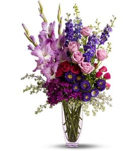 Purple and pink mixed flower arrangement in a clear vase