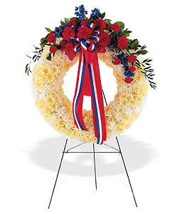 Patriotic wreath of yellow flowers with red and blue accents on a metal easel