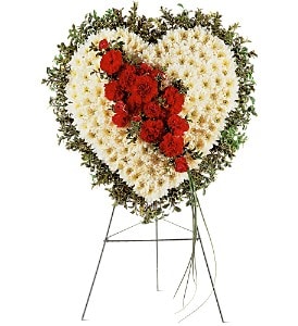 Heart-shaped standing floral spray of white blooms with red flowers on a metal easel.