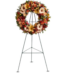 Standing wreath of peach and orange flowers with lilies and gerberas on a metal easel