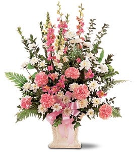 Tall pink and white carnations and daisies in an ivory vase with a pink ribbon bow