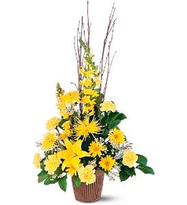 Tall yellow lily and carnation arrangement with branches in a brown basket