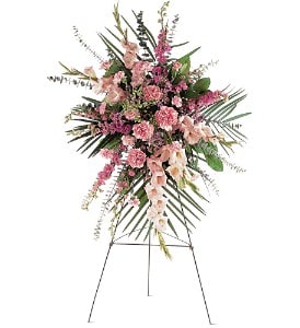 Tall pink carnation and snapdragon standing spray with palm fronds on a metal easel