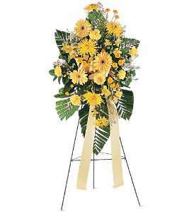Tall standing spray of yellow daisies and mums on an easel with long yellow ribbons