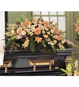 Peach and cream casket spray of lilies, roses, and daisies on a black casket