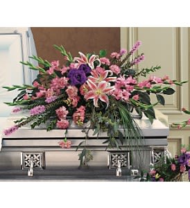 Pink and purple casket spray with lilies and carnations on a silver casket