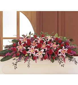 Long red and pink arrangement with lilies and roses displayed on a ledge