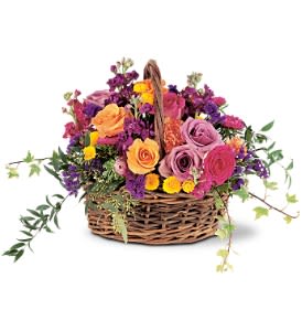 Bright mixed basket arrangement of roses and small yellow blooms in purple and orange tones
