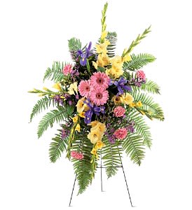 Tall standing spray with pink gerberas, yellow blooms and purple irises on a metal easel