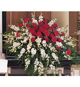Large spray of red roses and carnations with white flowers arranged on a casket