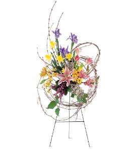Tall standing easel with a circular twig frame filled with bright mixed spring flowers