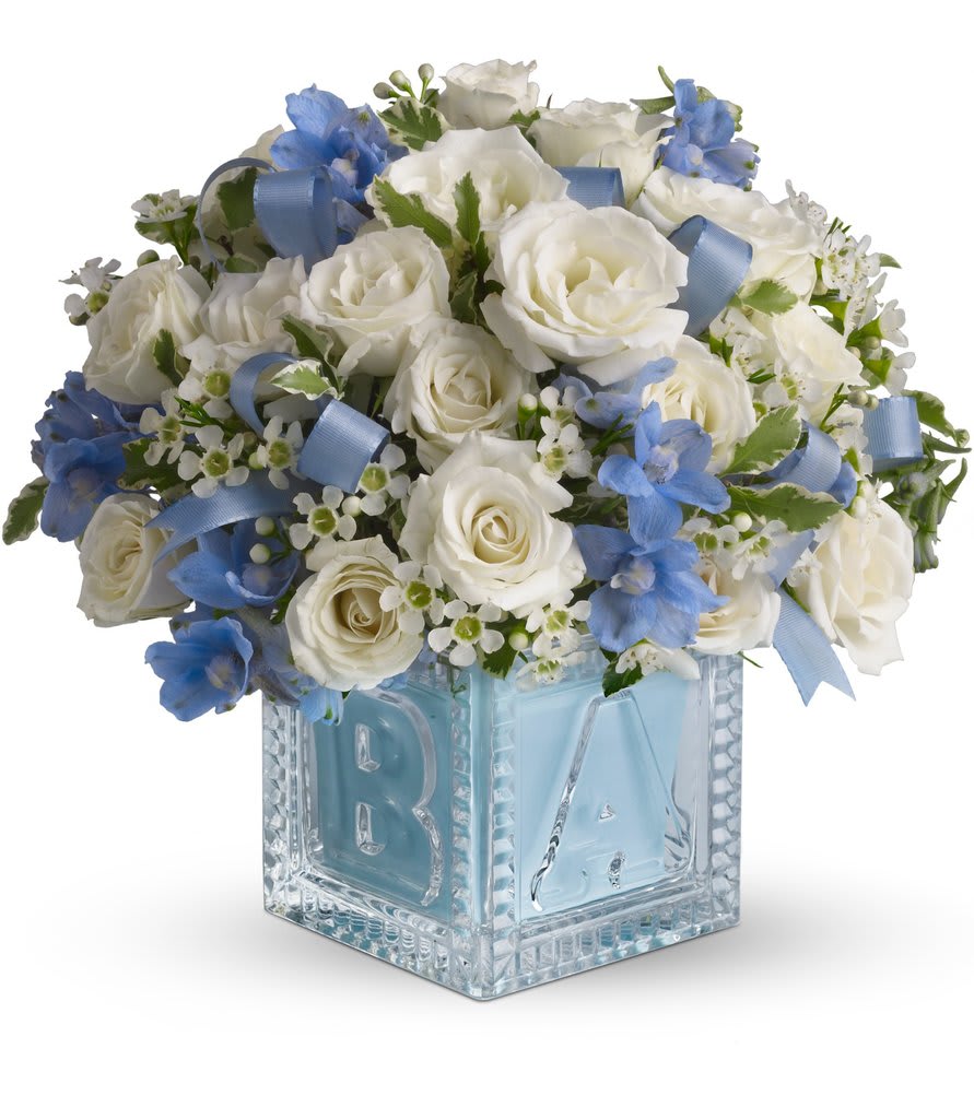 White roses and blue flowers in a glass block vase