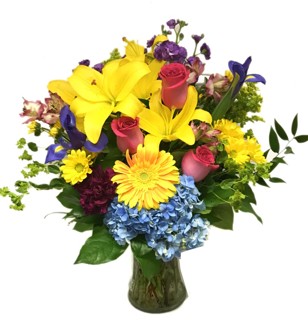 Colorful mixed bouquet in a glass vase with lilies, roses, and hydrangeas