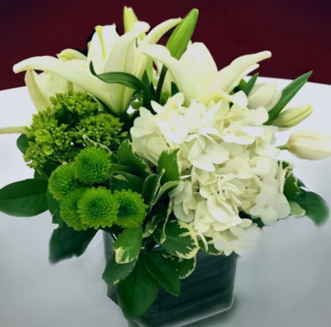 White lilies and hydrangeas with green pompons in a dark vase