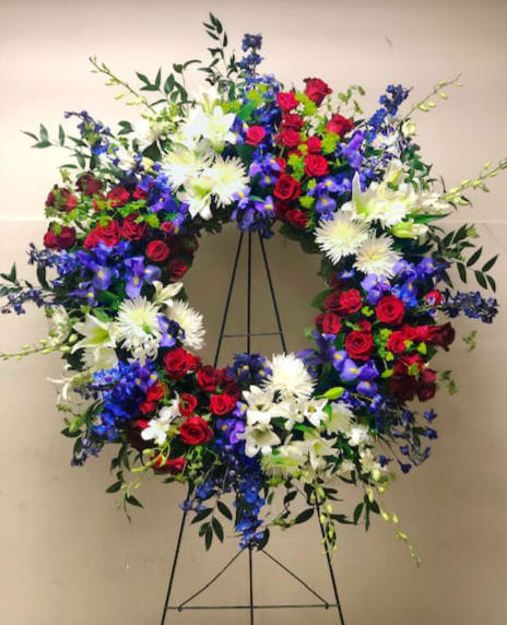 Large circular floral wreath on a stand with red, white, and blue flowers