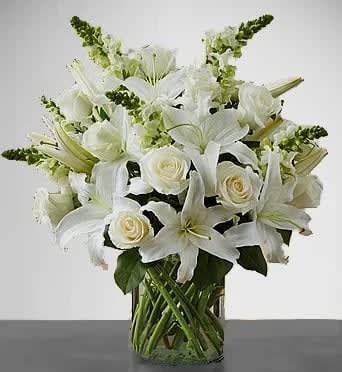 White lilies and roses arranged in a clear glass vase