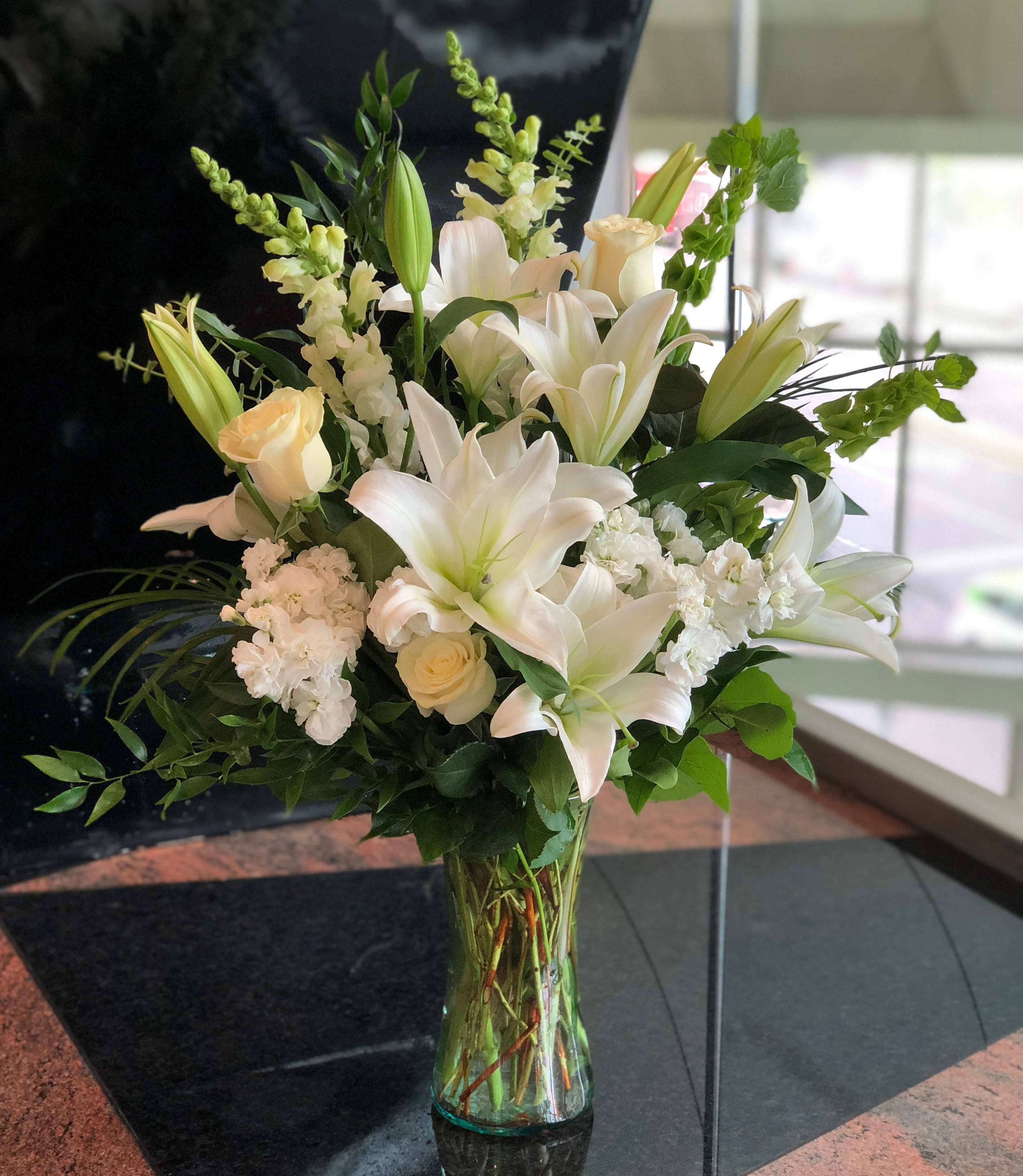 White lilies and cream roses in a clear glass vase