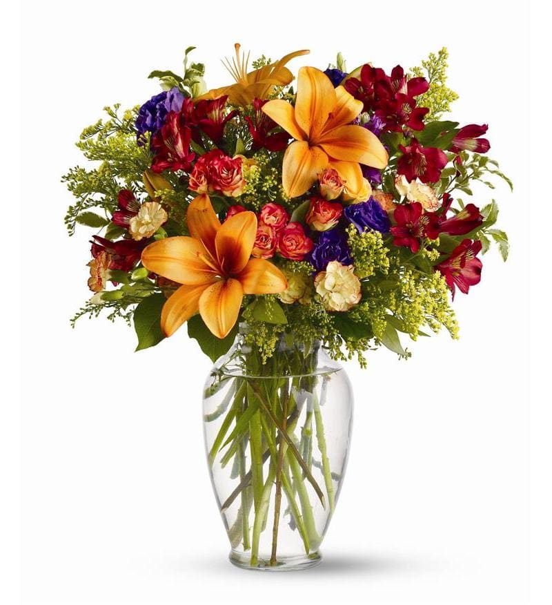 Mixed bouquet of lilies, roses, and alstroemeria in a clear glass vase