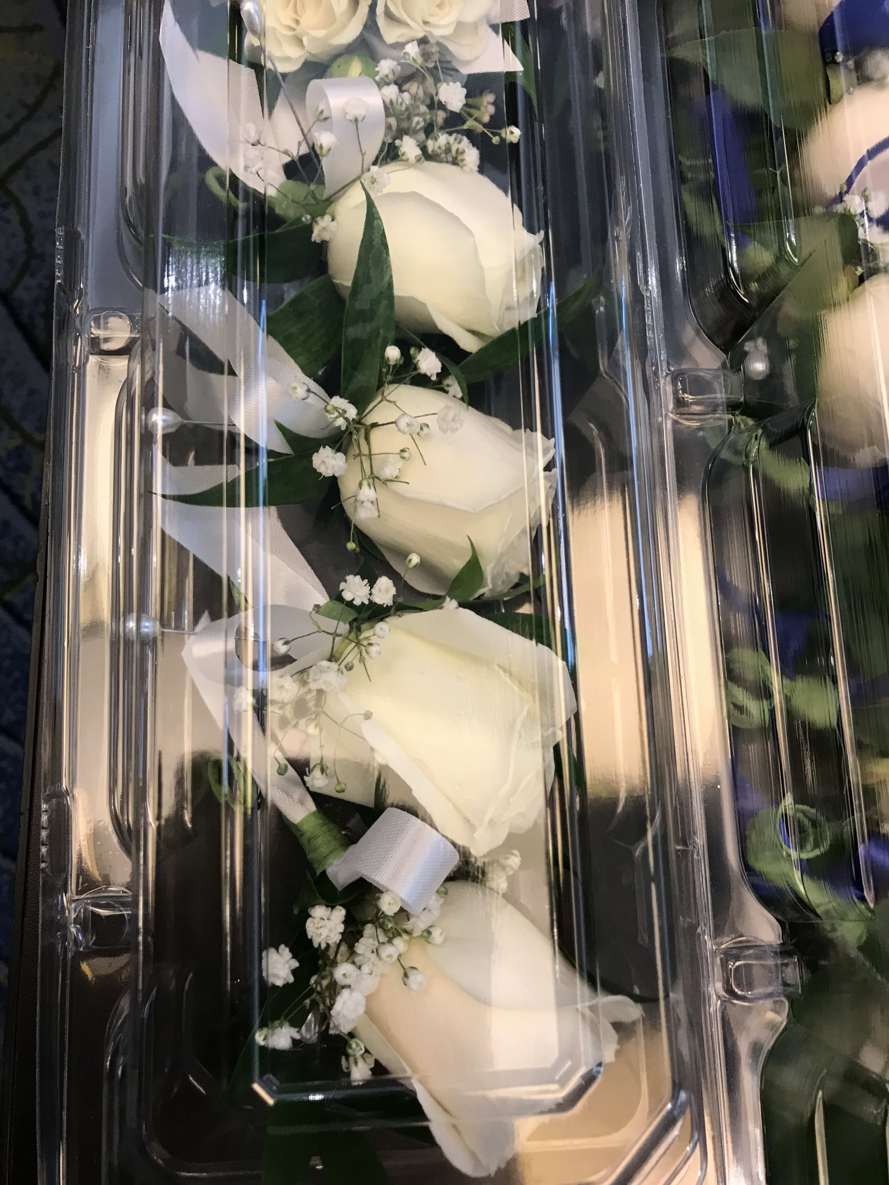 White rose boutonniere set in a clear plastic box