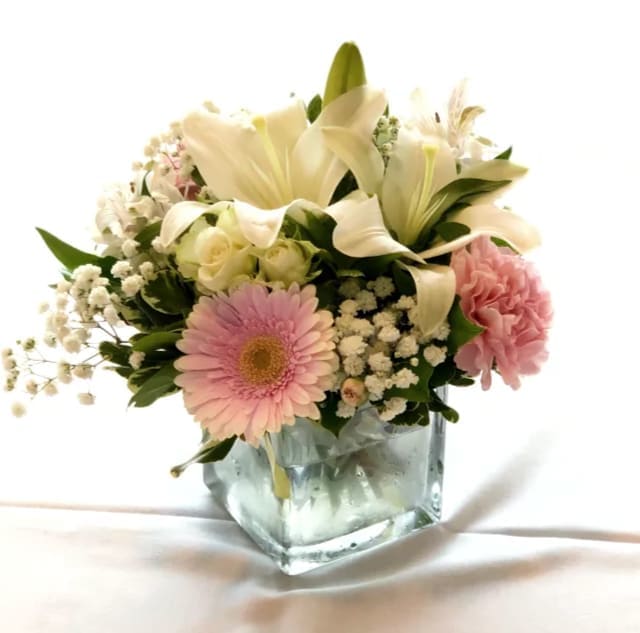 Pink and white flower arrangement in a square glass vase