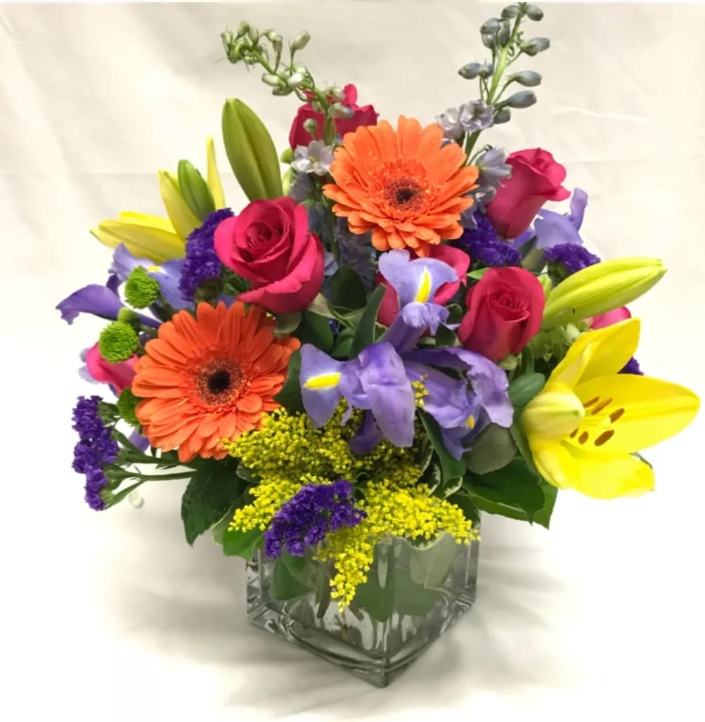 Colorful bouquet of roses, lilies, and gerbera daisies in a glass vase