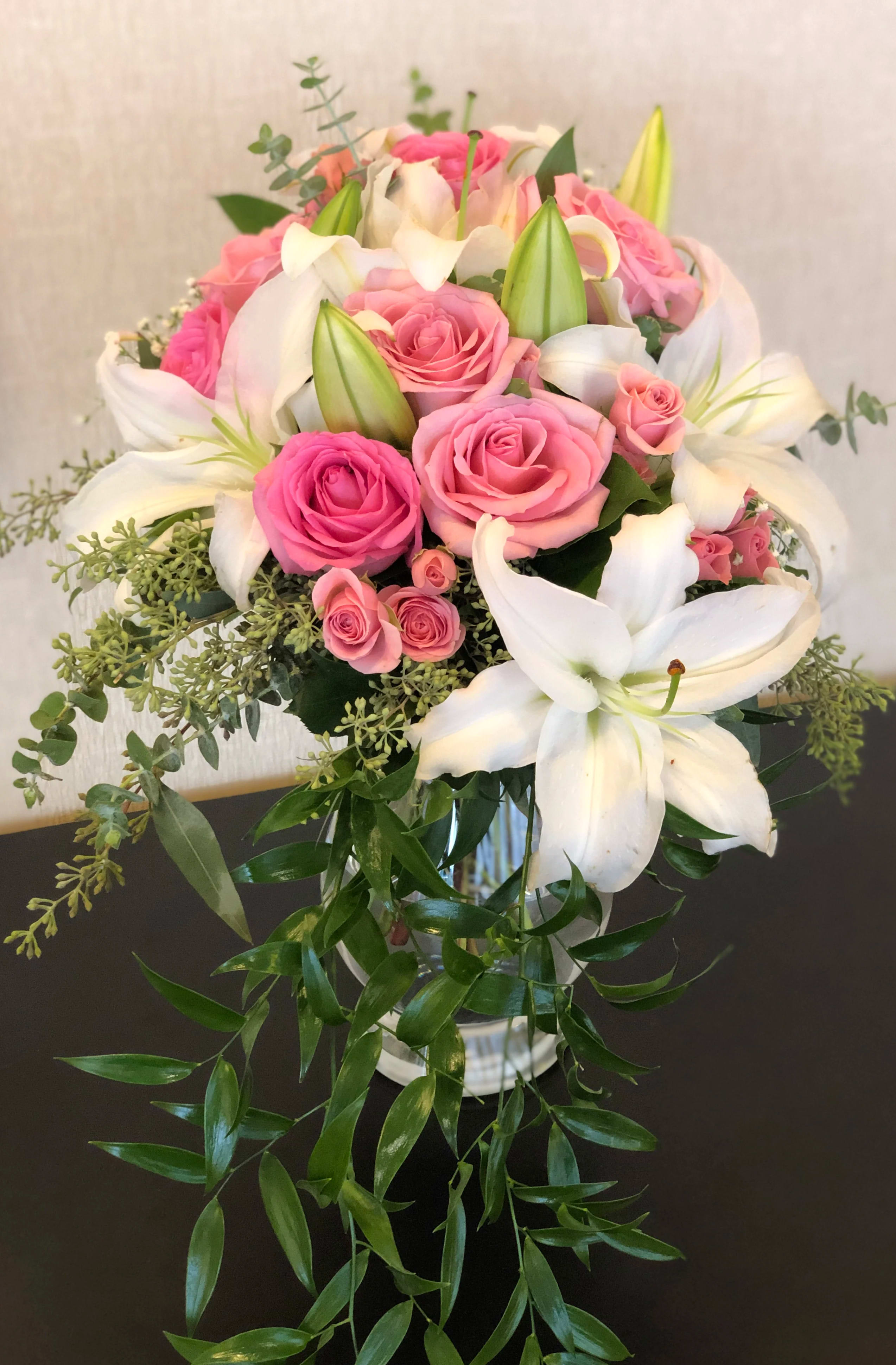 Pink roses and white lilies arranged in a glass vase