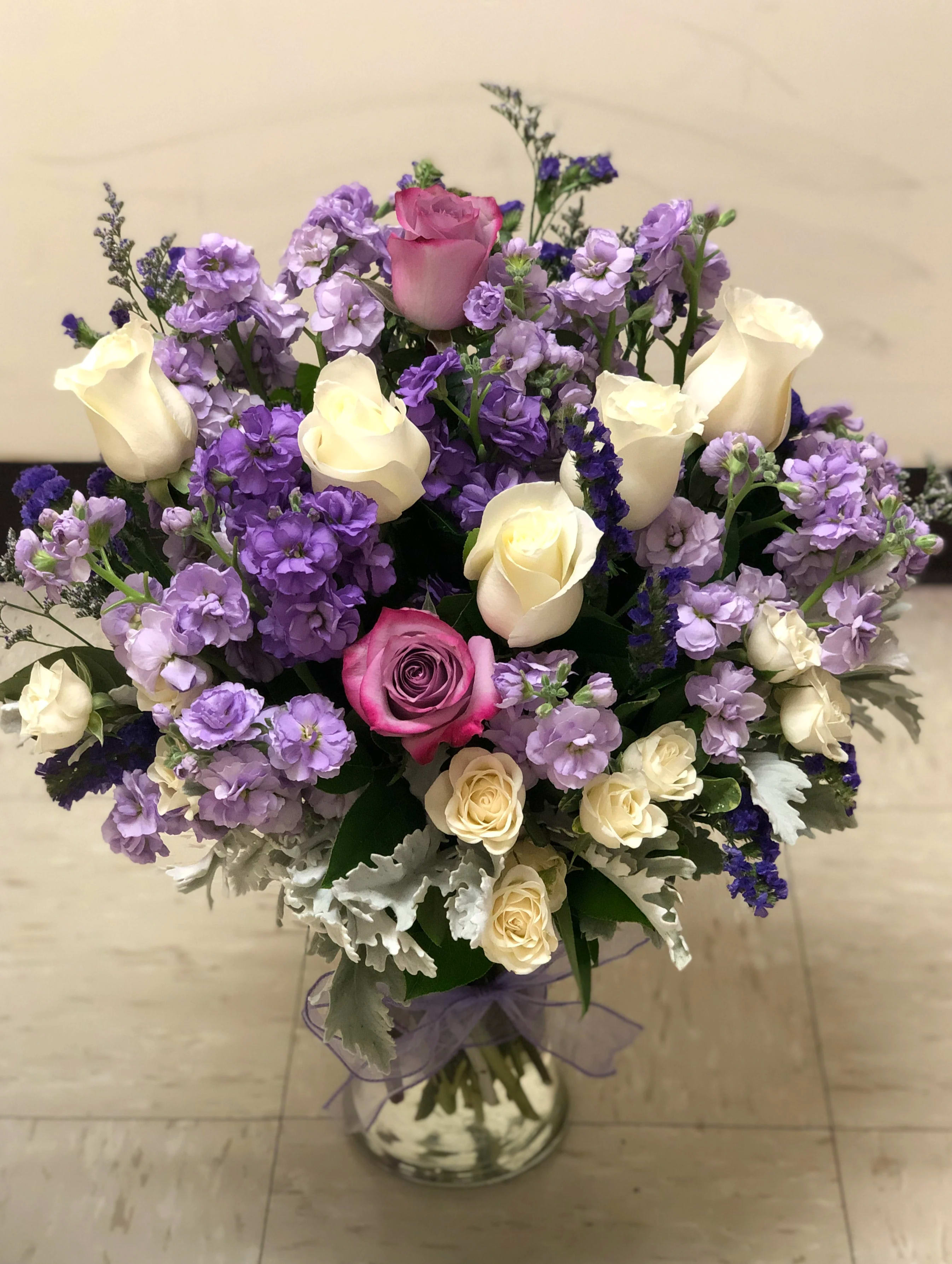 Bouquet of pink and cream roses with purple flowers in a glass vase