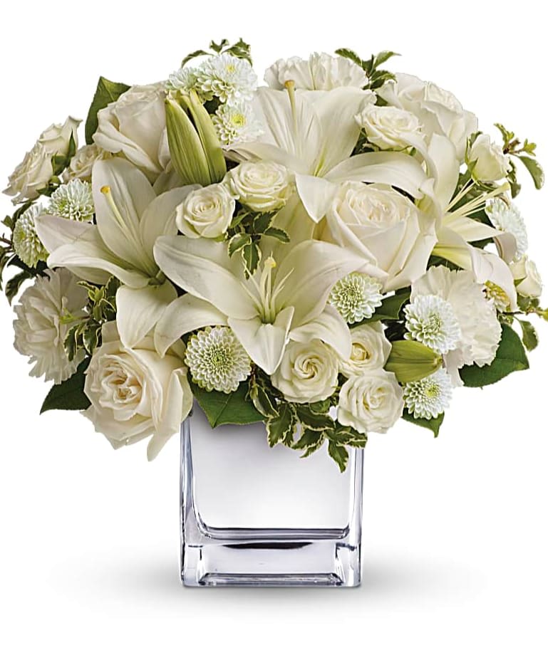White lilies and roses arranged in a clear glass vase