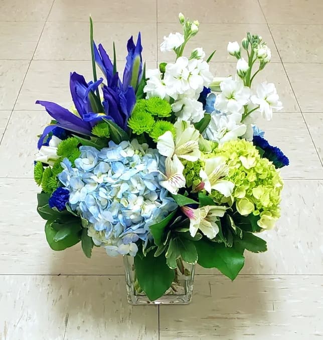 Blue and white floral arrangement in a clear square vase