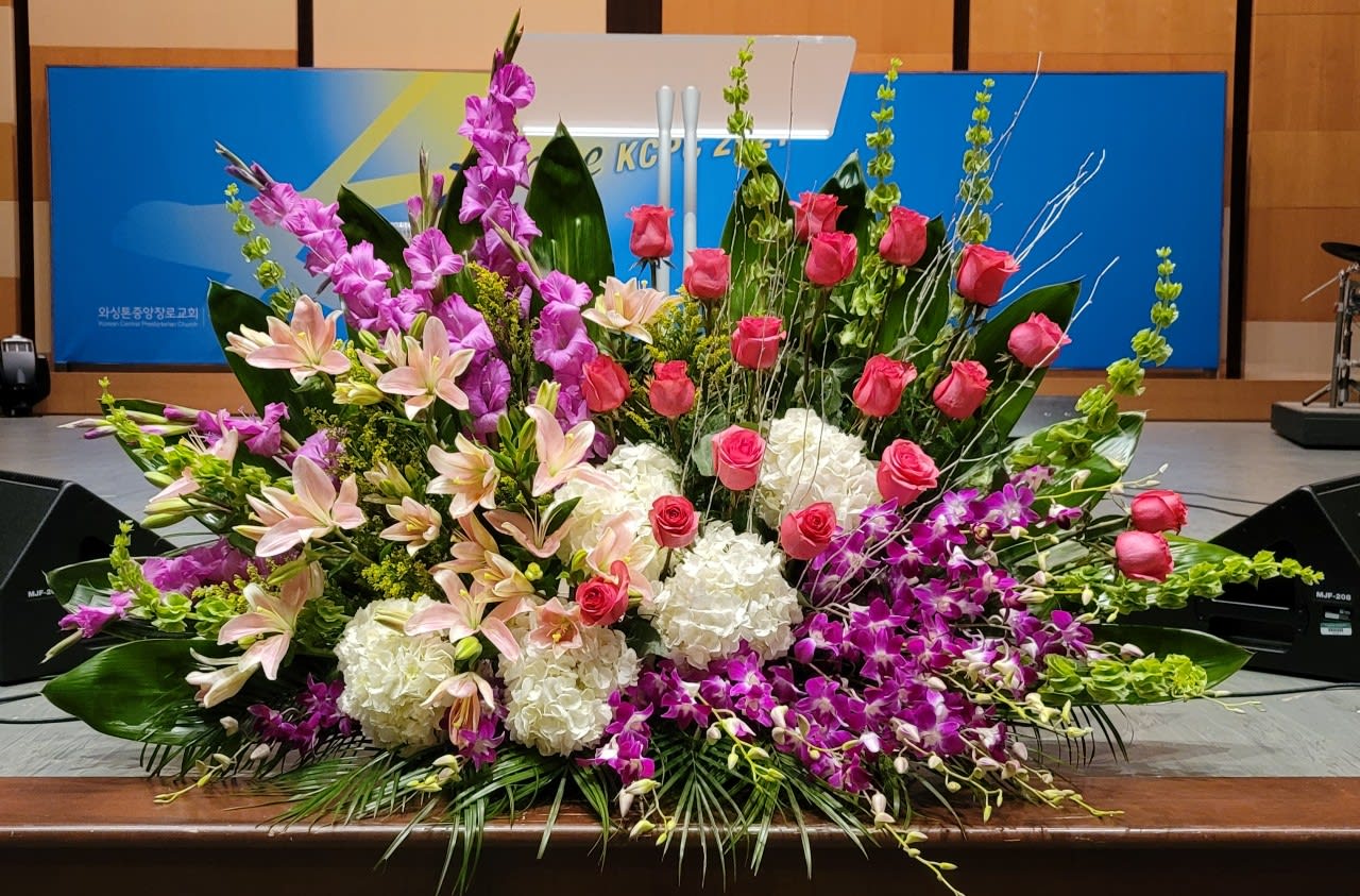 Large altar-style arrangement with pink roses, lilies, orchids and white hydrangeas
