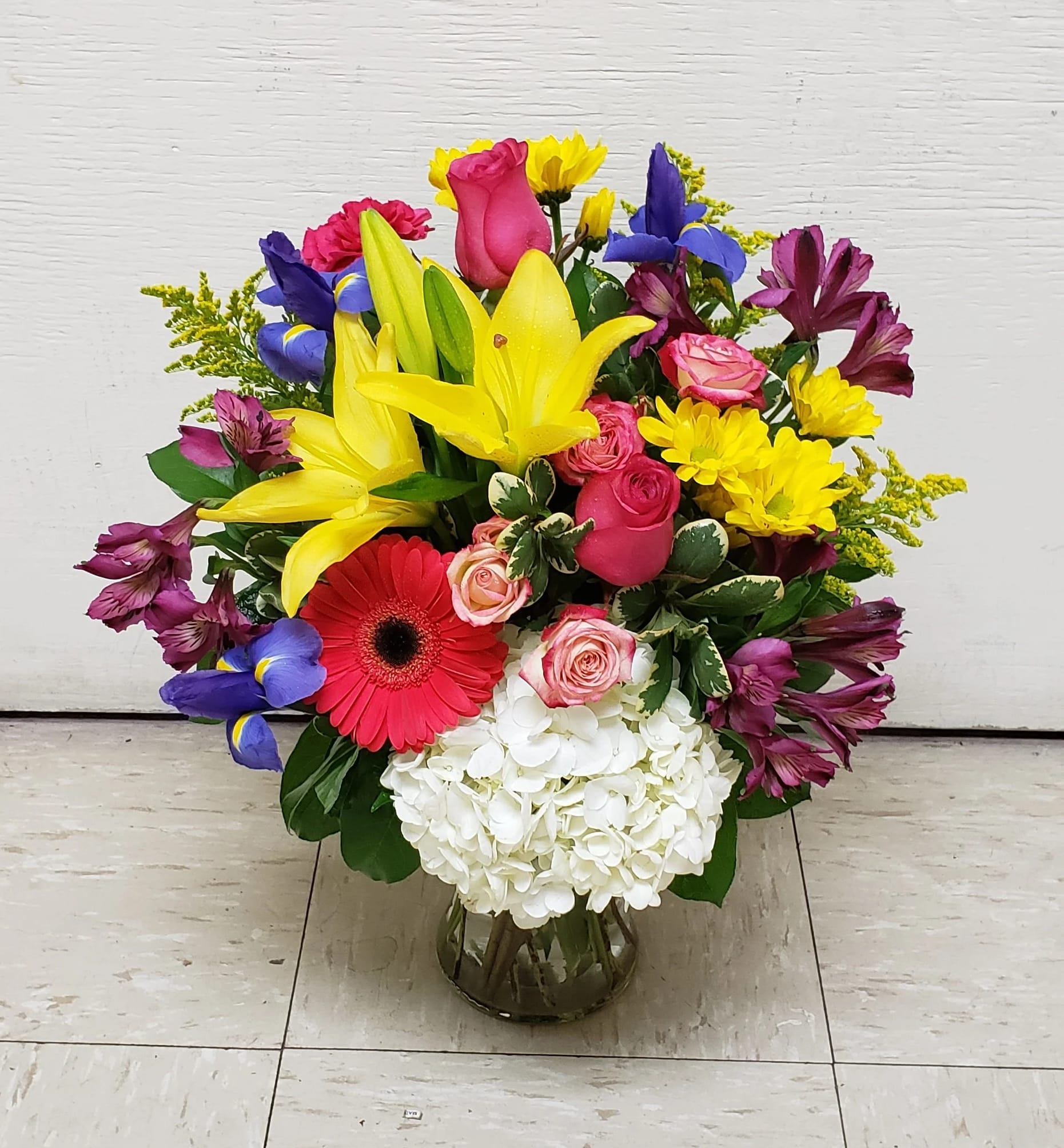 Mixed bouquet with lilies, roses, gerbera daisies, and hydrangea in a glass vase