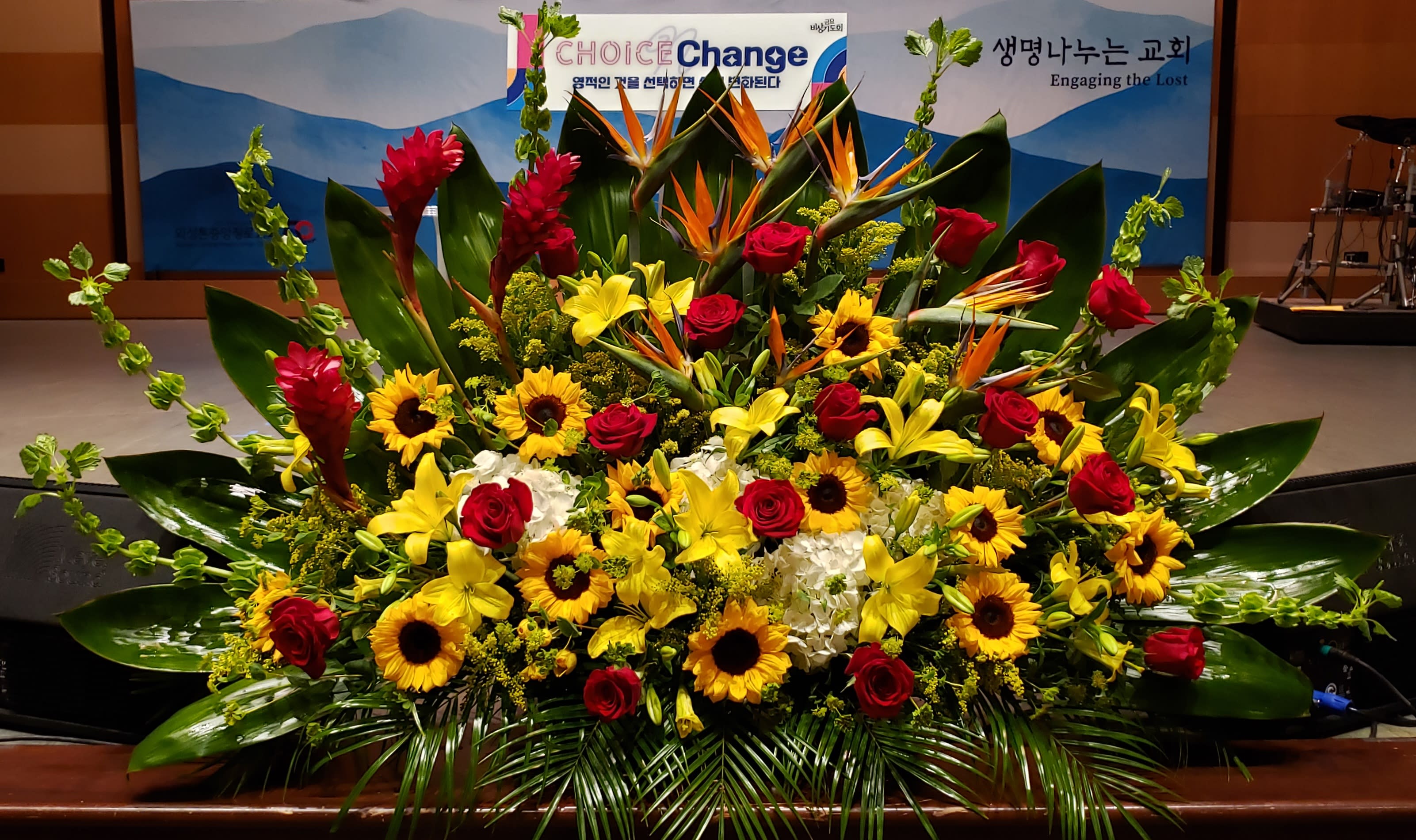 Large altar arrangement with yellow lilies, sunflowers, red roses and tropical flowers in a fan shape