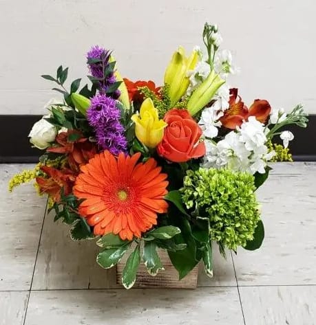 Mixed bouquet in a square box with orange, red, yellow, white, and purple flowers