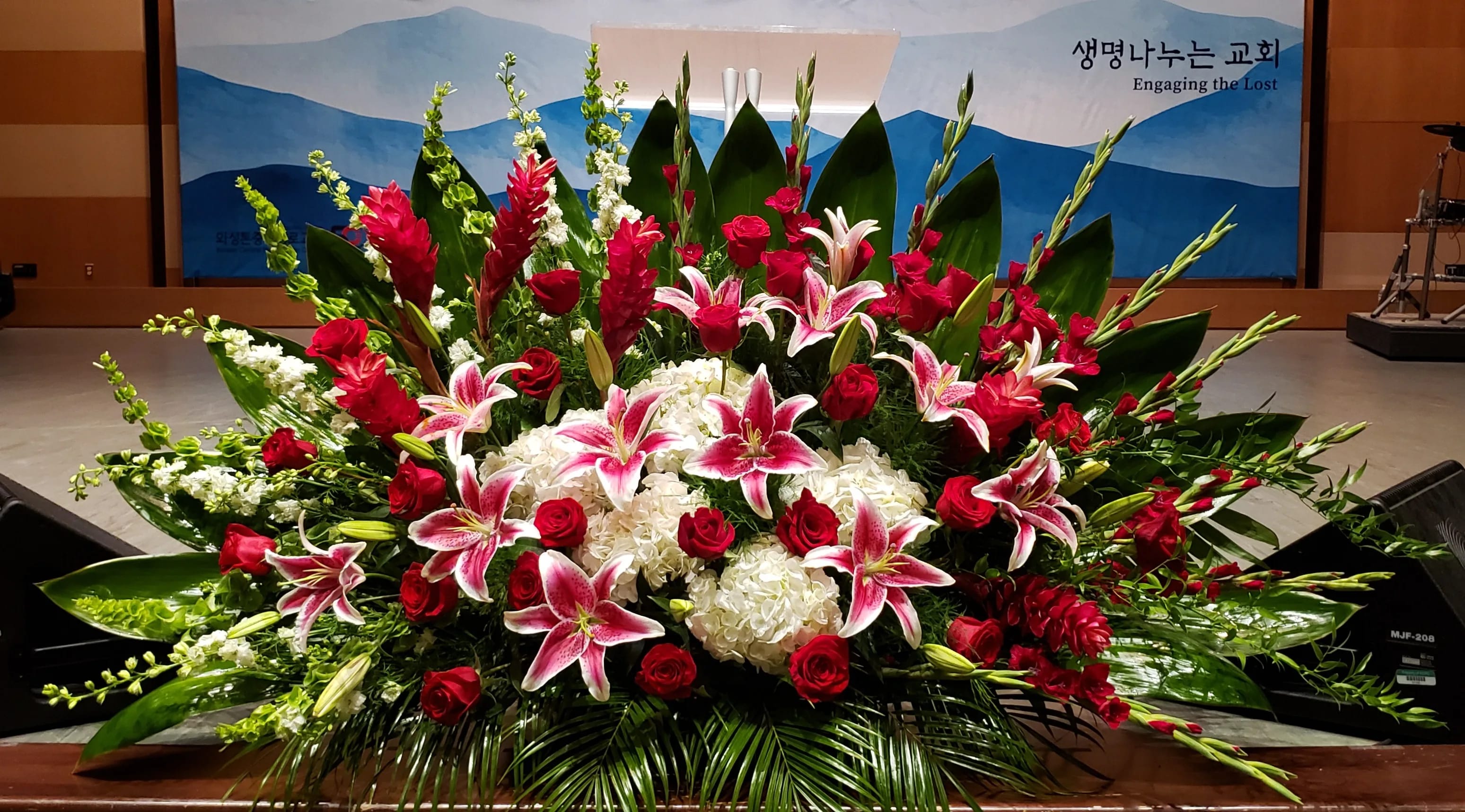 Large floral spray with pink lilies, red roses, and white hydrangeas