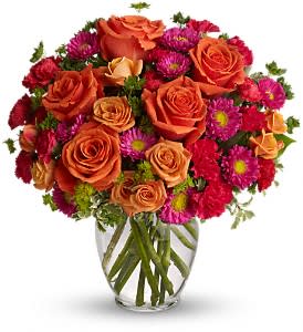 Bouquet of orange roses and magenta daisies in a clear glass vase