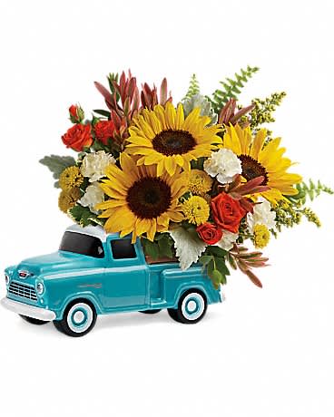 Bright sunflowers and mixed blooms arranged in a turquoise ceramic pickup truck container