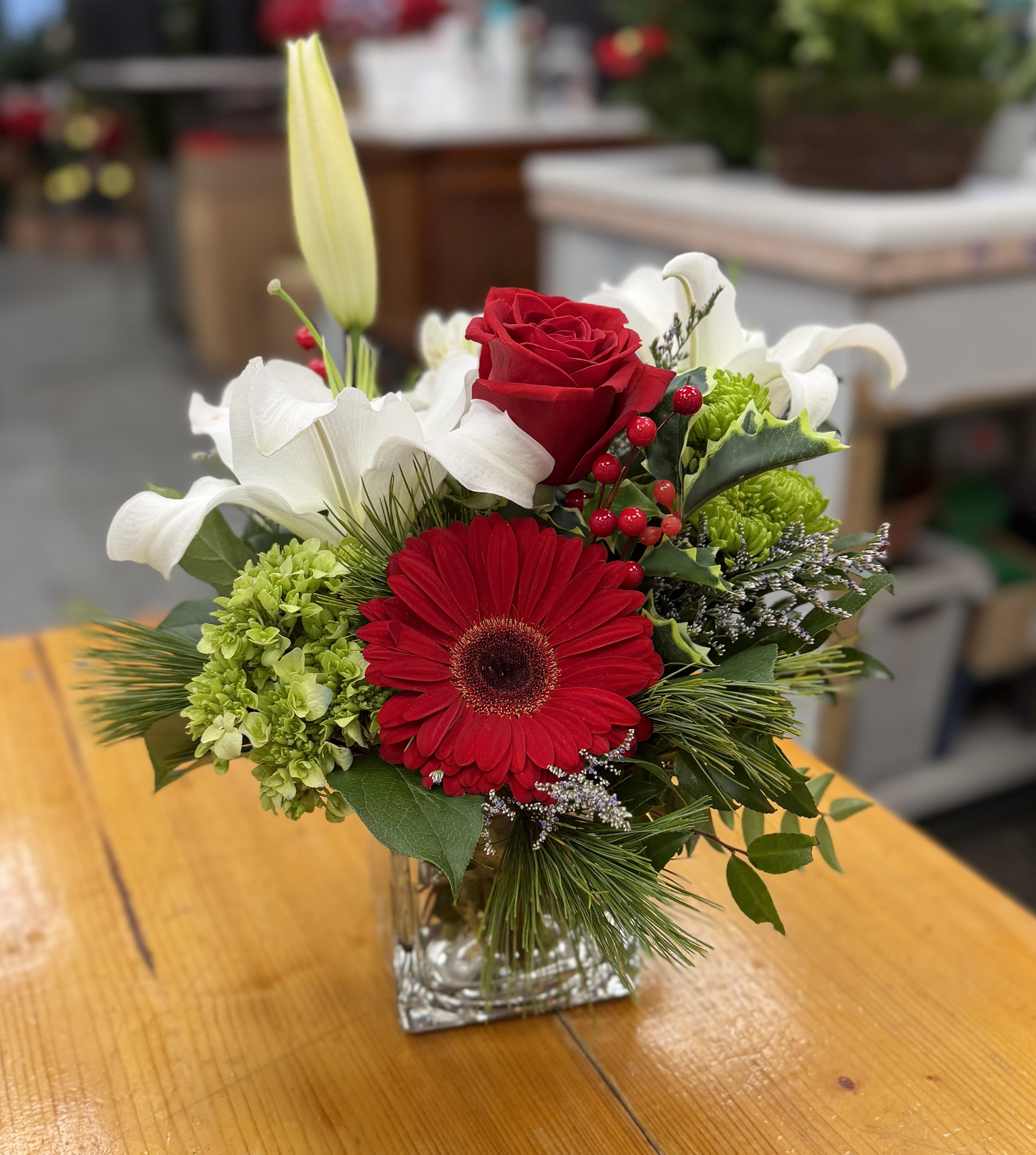 Red gerbera and rose bouquet in a clear square vase