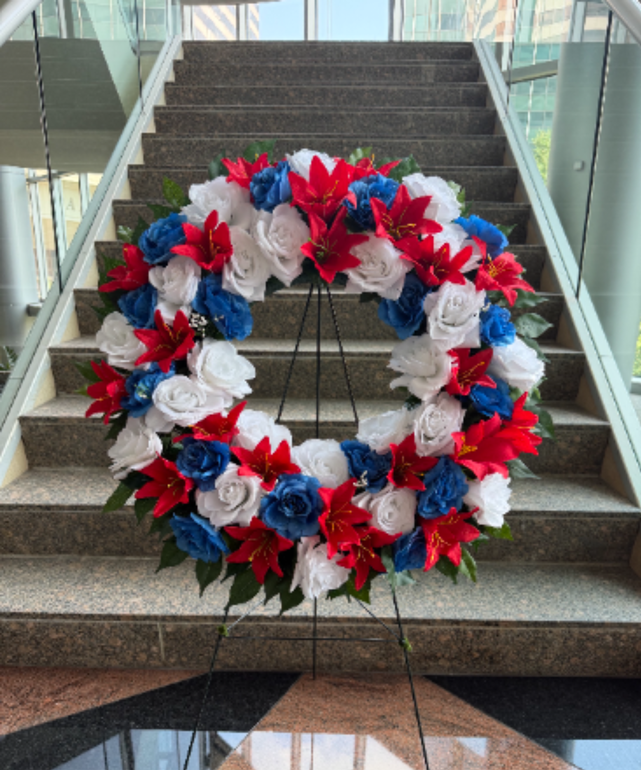  24" RED WHITE AND BLUE SILK WREATH ON EASEL - 24" RED WHITE AND BLUE SILK WREATH ON EASEL BY TWIN TOWERS FLORIST  SILK (ARTIFICIAL) FLORAL WREATH      As Shown : TT-ANCSILK2  Available for local delivery only