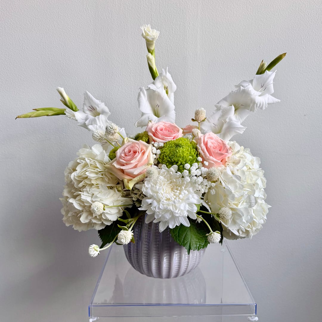 White and pink floral arrangement in a ribbed vase