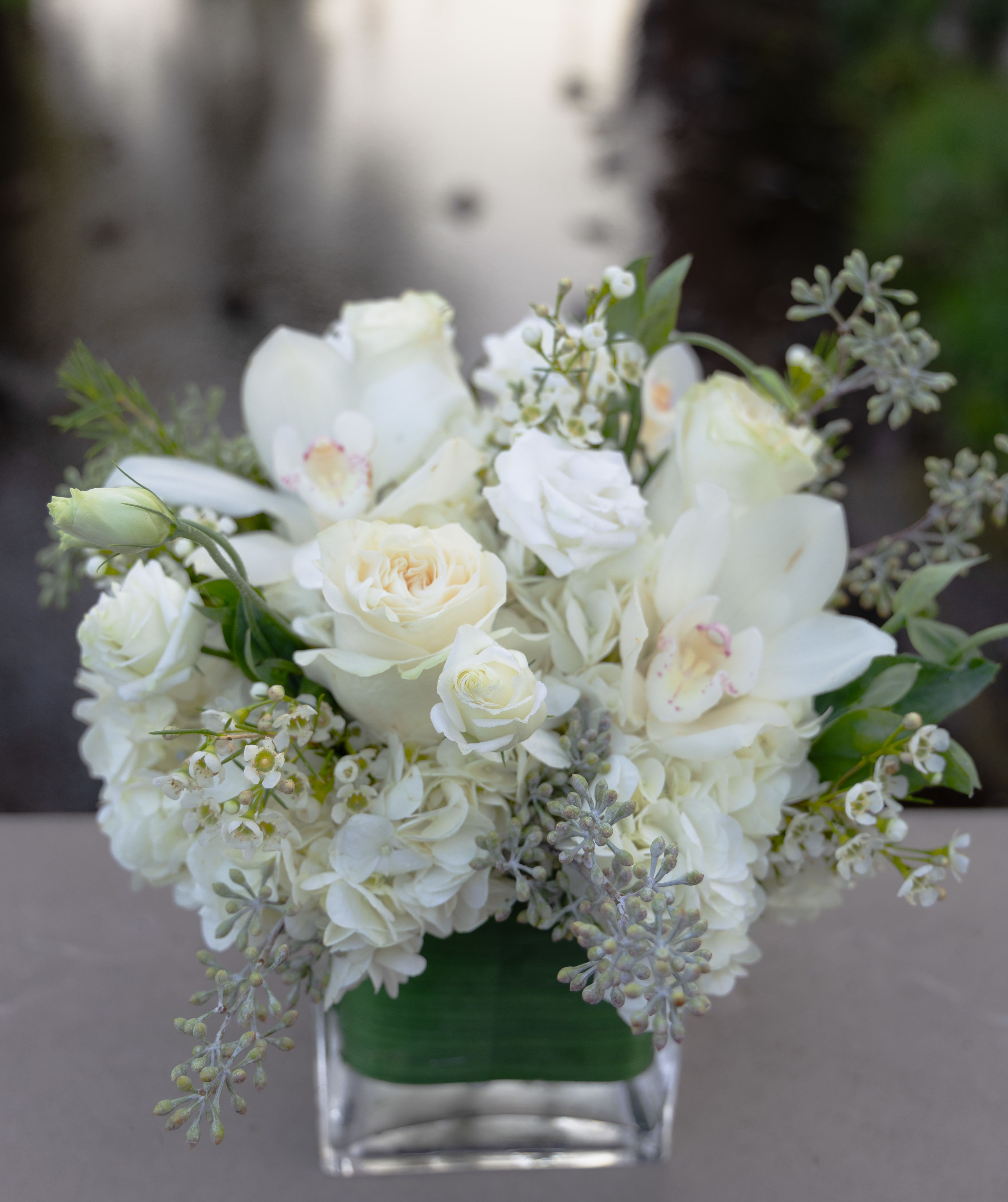 White floral arrangement in a clear square vase