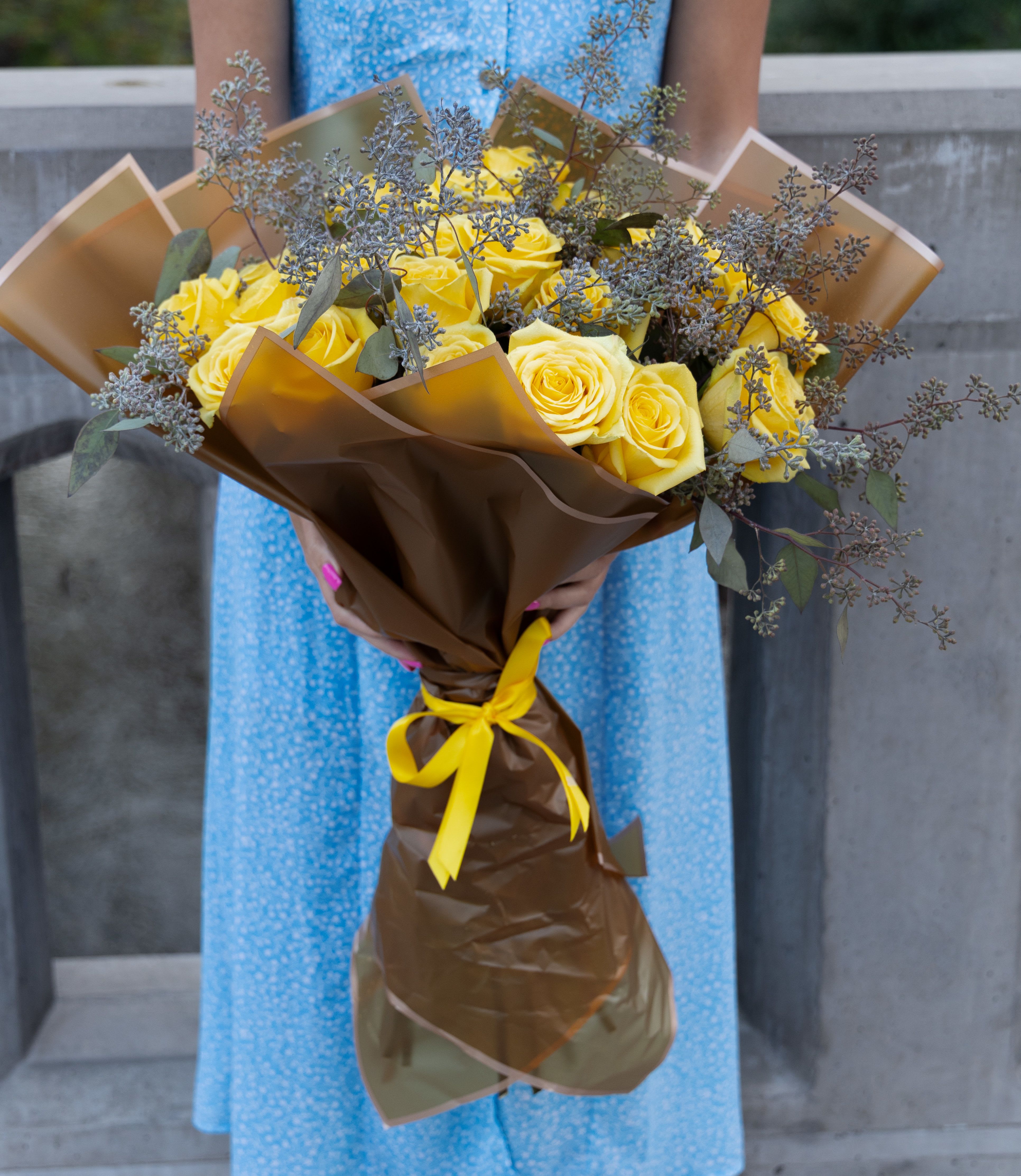 Bouquet of yellow roses wrapped in brown paper with a yellow ribbon