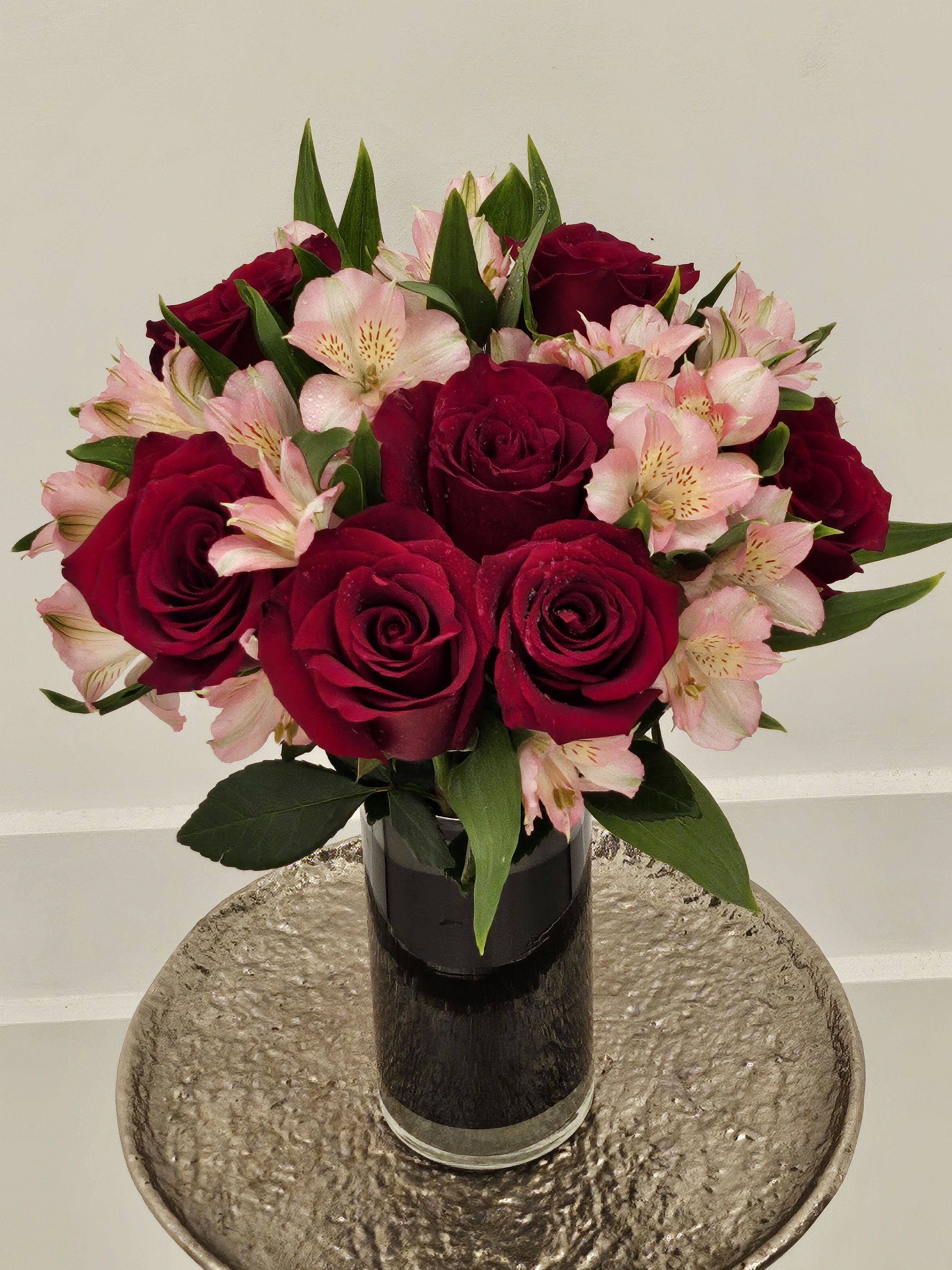 Bouquet of red roses and pink alstroemeria in a black vase