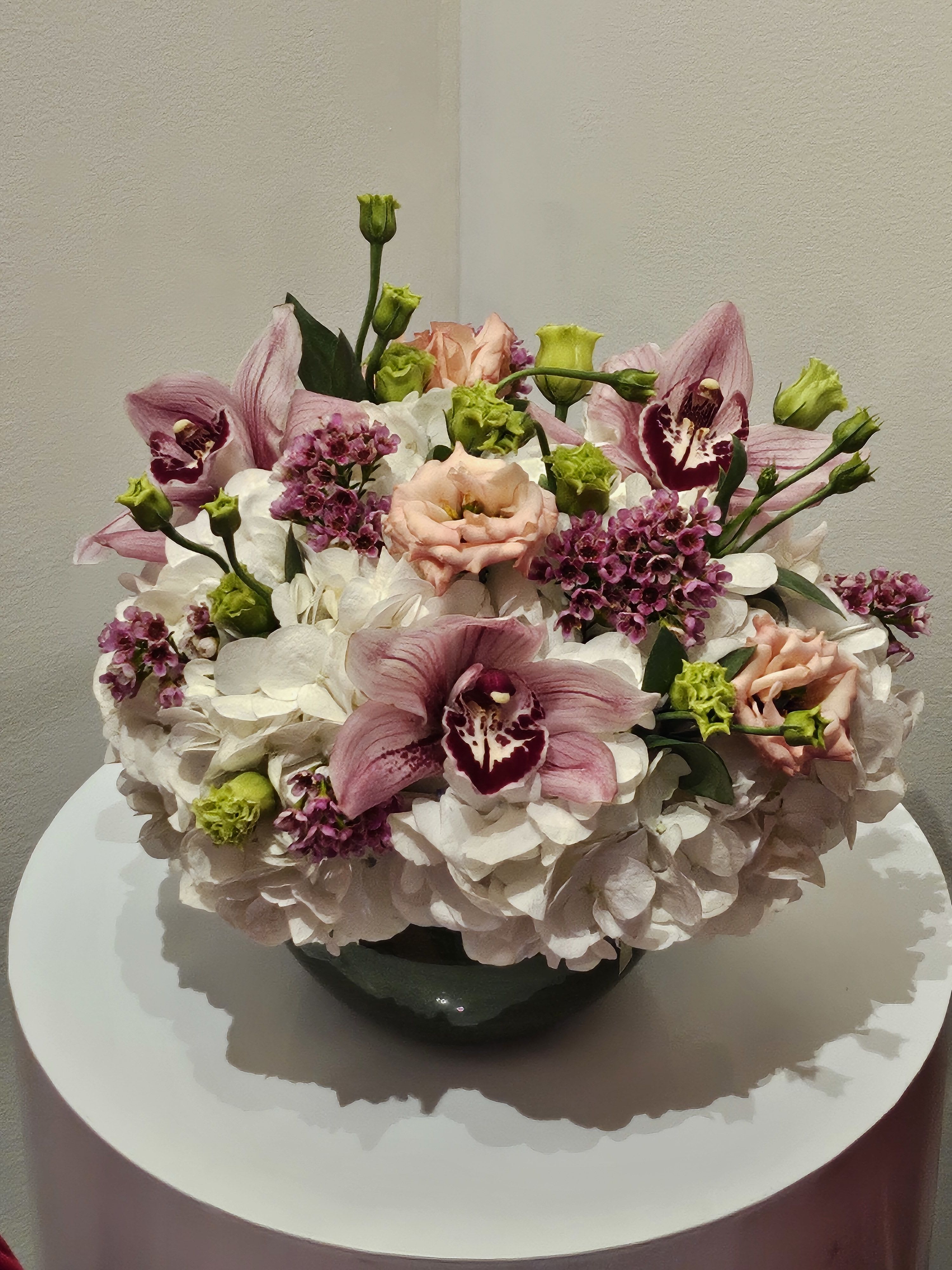 Pink orchids and white hydrangeas arranged in a dark vase
